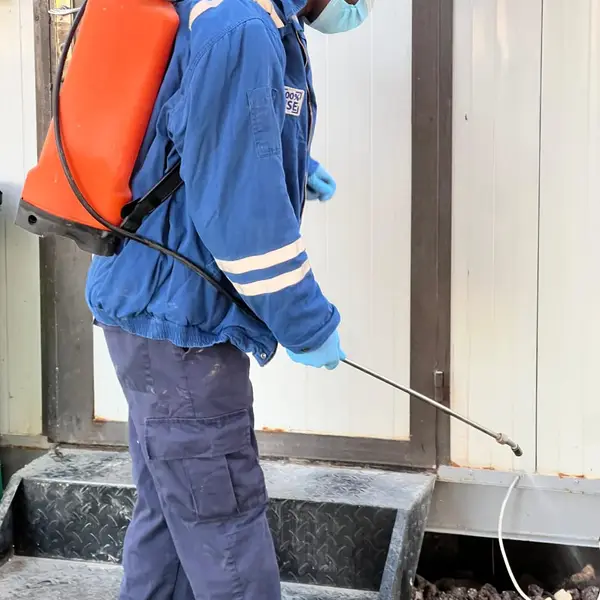 Technician in protective gear treating a camp unit